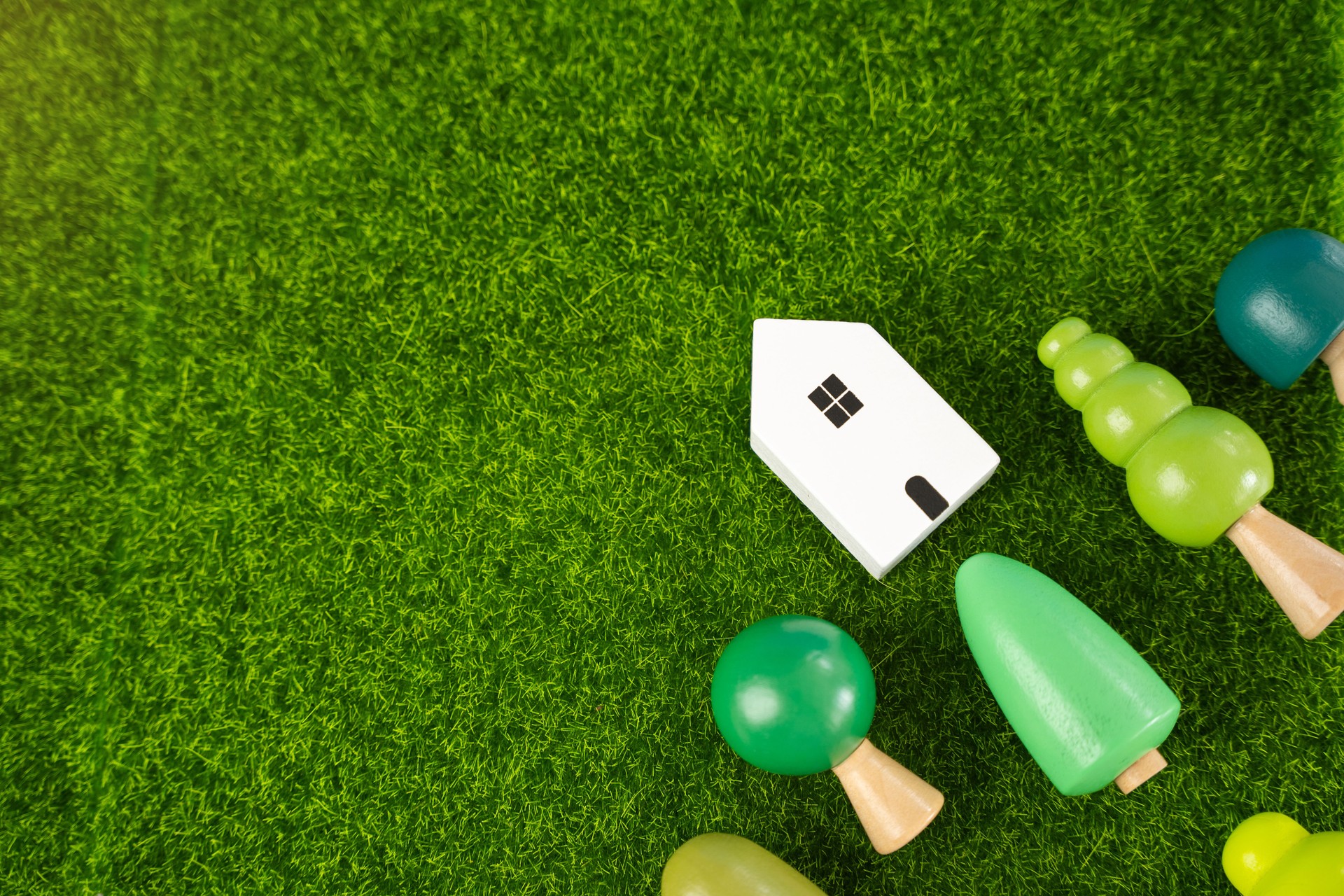 Figuras de una casa de madera y árboles sobre la hierba. Casa ecológica. Recreación en la naturaleza. El concepto de primavera y respeto por el medio ambiente, la cercanía con la naturaleza.